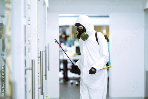 Disinfecting of office to prevent COVID-19, Man in protective hazmat suit with  with spray chemicals to preventing the spread of coronavirus, pandemic in quarantine city. Cleaning concept. © maxbelchenko