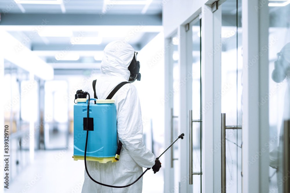 Disinfecting of office to prevent COVID-19, Man in protective hazmat suit with with spray chemicals to preventing the spread of coronavirus, pandemic in quarantine city. Cleaning concept. Disinfecting of office to prevent COVID-19, Man in protective hazmat suit with with spray chemicals to preventing the spread of coronavirus, pandemic in quarantine city. Cleaning concept.
