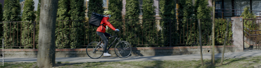 Delivery man courier wearing medical mask arrives at residential address to deliver food order to customers during virus outbreak. Coronavirus, COVID-19, safe delivery Delivery man courier wearing medical mask arrives at residential address to deliver food order to customers during virus outbreak. Coronavirus, COVID-19, safe delivery