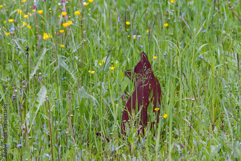 Fototapeta premium A funny cat statue in a meadow