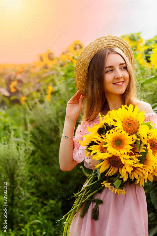 Beautiful smiling young woman in a white shirt stands in the field among sunflowers Beautiful smiling young woman in a white shirt stands in the field among sunflowers