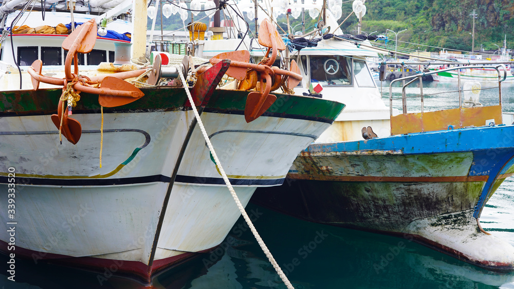 Asian fishing boats anchored in port. Taiwanese multi-colored fishing trawler moored in bay on background of green mountains,
Fishing industry in Asia. fishermen prepare gear
