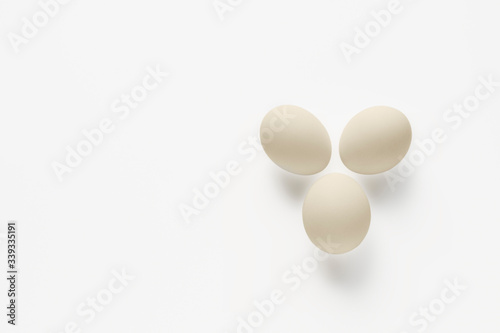 Three white eggs on a light background