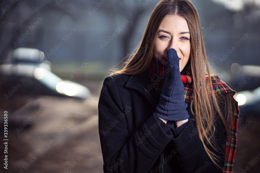 Photo of cute blond girl in black jacket and red scarf looking like she is cold