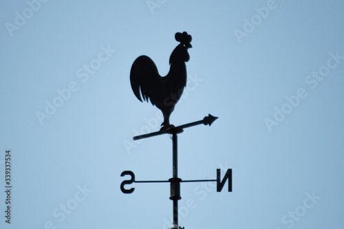 Metal rooster in a vane on a rooftop