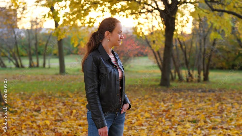 Young adult woman pose in autumn park, turn head and look aside. Pretty lady wear black jacket, half length portrait shot. Blurred background Young adult woman pose in autumn park, turn head and look aside. Pretty lady wear black jacket, half length portrait shot. Blurred background