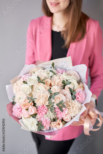 Beautiful bouquet of mixed flowers in womans hands. the work of the florist at a flower shop. Delivery fresh cut flower. European floral shop.