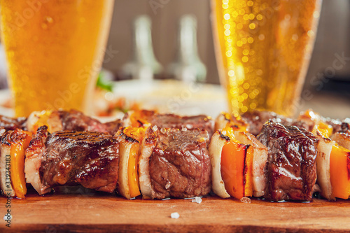 Grilled meat stick with two glasses of beer in close-up - Brazilian espetinho de carne photo