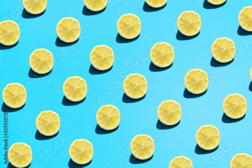 Lemon pattern on bright light blue background. Minimal flat lay food texture. Summer abstract trendy fresh concept.