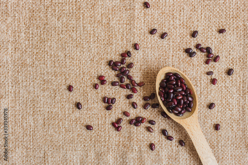 red bean seeds in a wooden spoon on the table burlap. close up