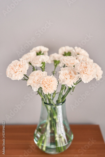 beautiful carnation flowers in a vase on a wooden table . Bouquet of pink flower. Decoration of home. Wallpaper and background.