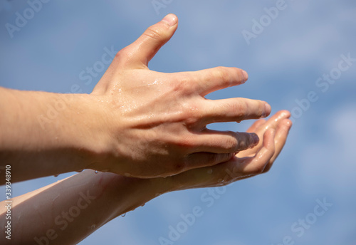 Strong male hands against a cloudy sky. © FO_DE