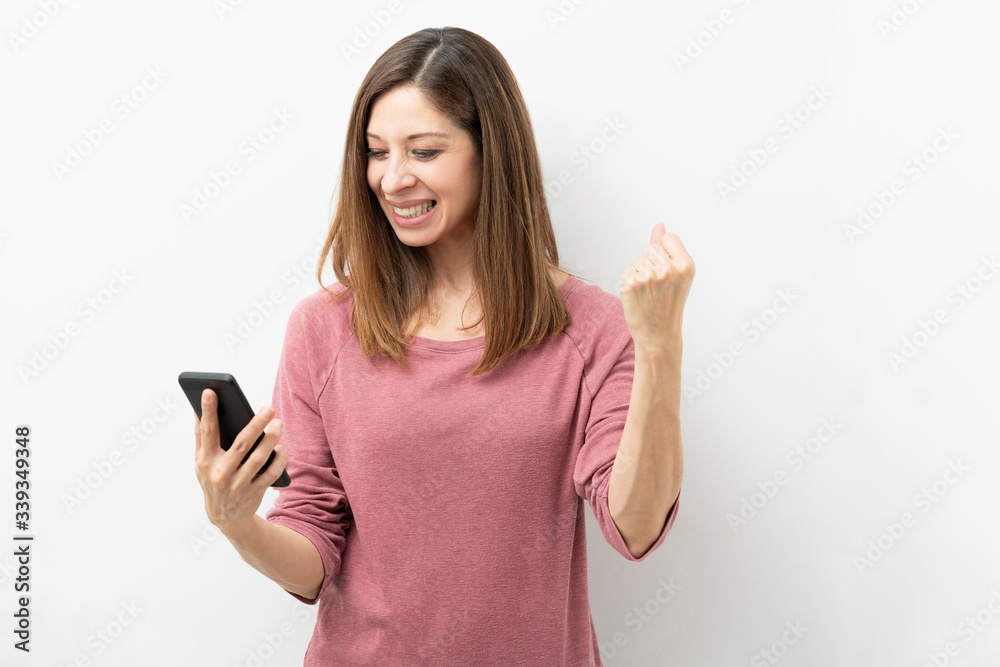 Woman looking excited while looking at her phone Woman looking excited while looking at her phone