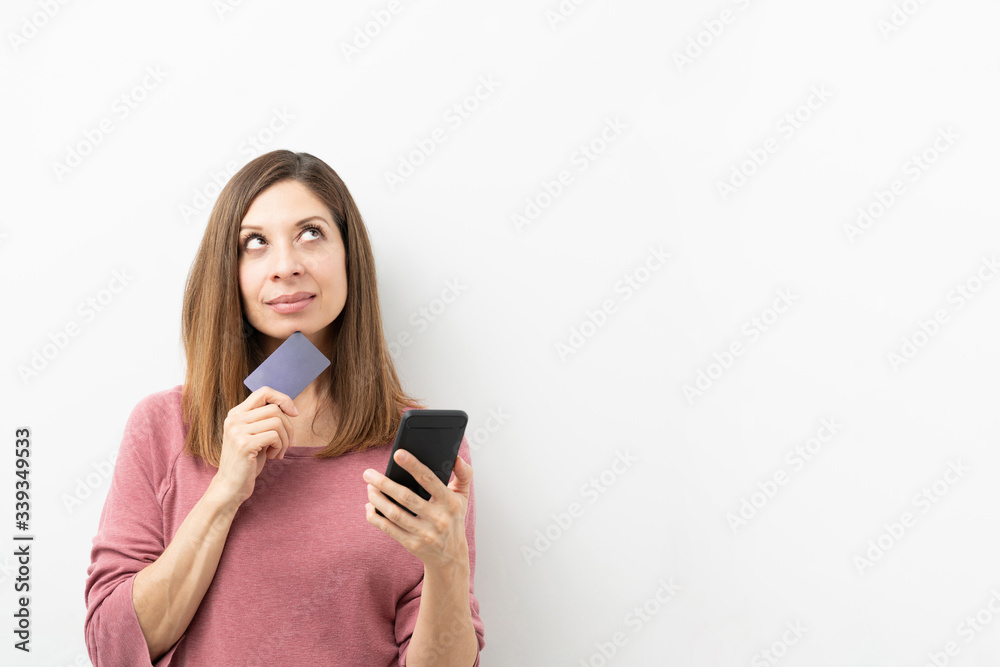 Woman thinking what to buy with credit card Woman thinking what to buy with credit card