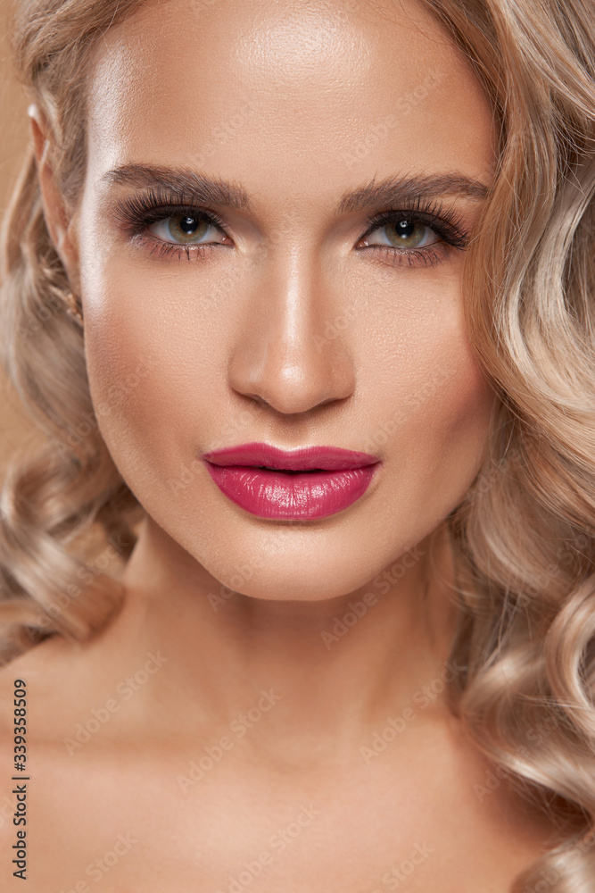 Fashion closeup portrait of blonde beautiful woman with glamour make-up and long wavy hair looking at you. Pretty spa female model with perfect fresh clean skin