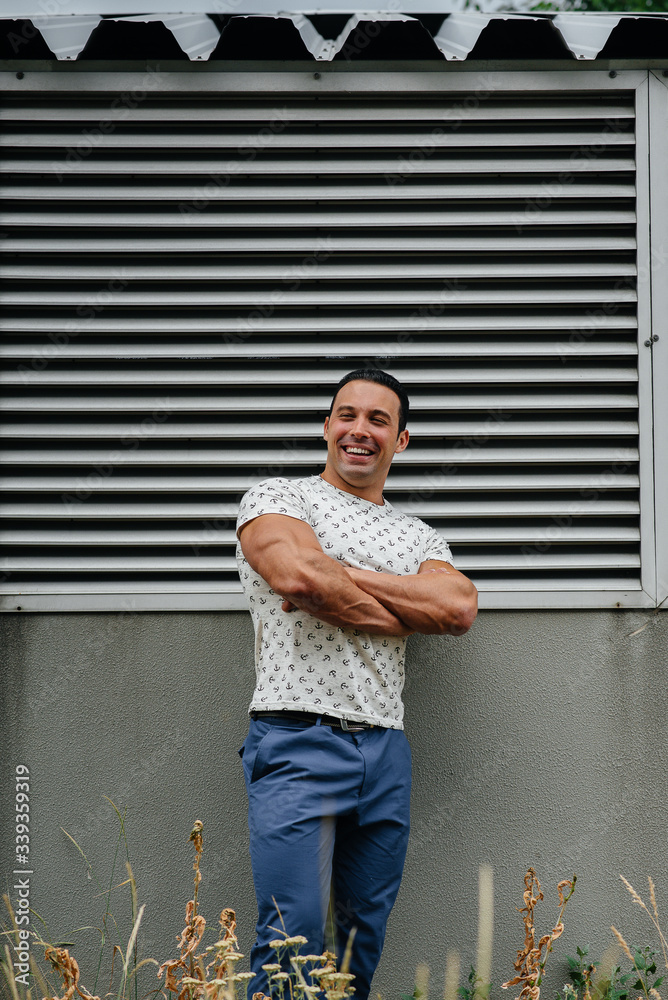 Fototapeta premium A sporty guy stands near a gray wall. Lifestyle