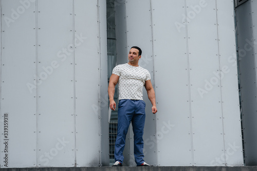 A sporty guy stands near a gray wall. Lifestyle © Andrii