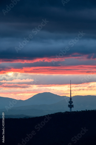 Fototapeta Naklejka Na Ścianę i Meble -  Canberra tower silhouette at sunset with layers of clouds and hills in the background