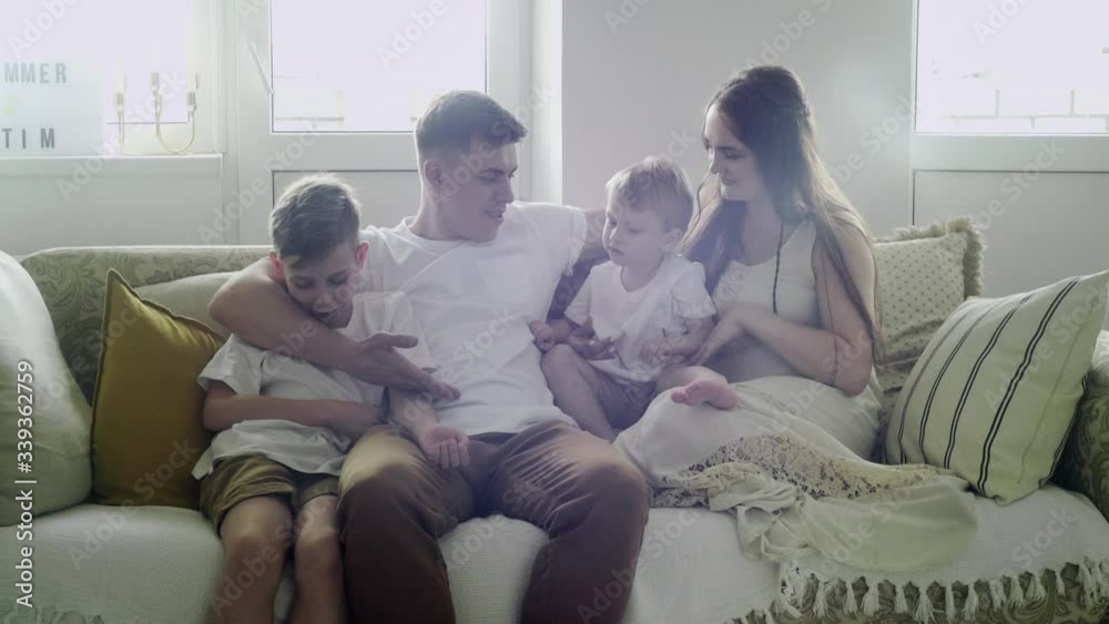 Good looking caucasian family of mother, father and two sons sitting on the sofa in the living room Good looking caucasian family of mother, father and two sons sitting on the sofa in the living room