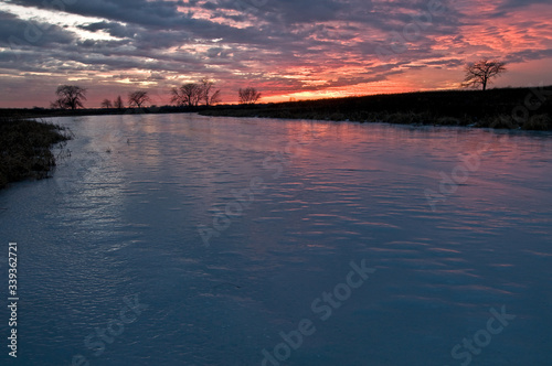 A peaceful end to a winter day as the colors of sunset reflect off the surface of a frozen wetland habitat. © Mark Baldwin