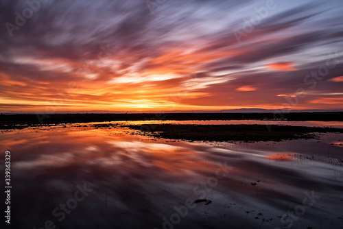 Majestic sunset with clouds in moviment reflected in the water photo