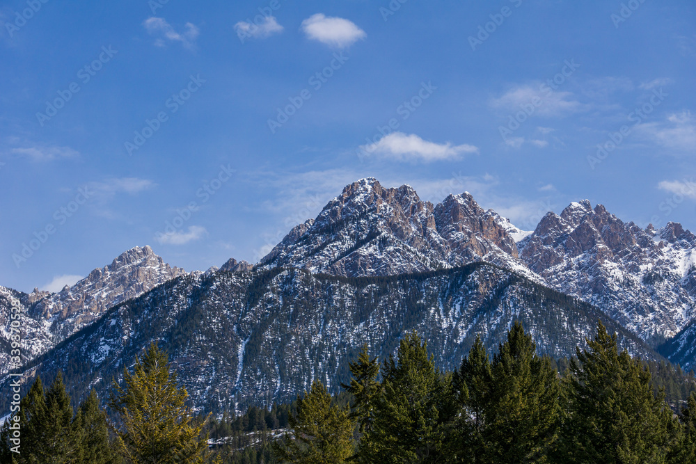 close-up view of the mountain peak with trees and snow on it sunny spring day.