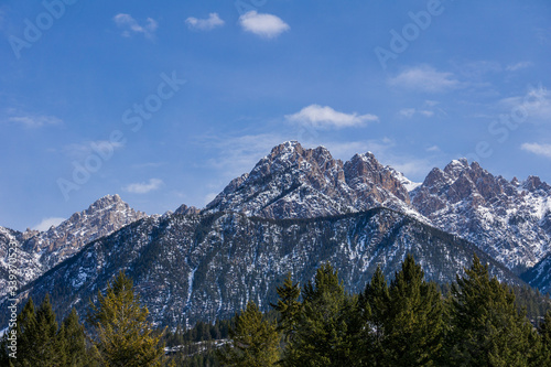close-up view of the mountain peak with trees and snow on it sunny spring day. © olegmayorov