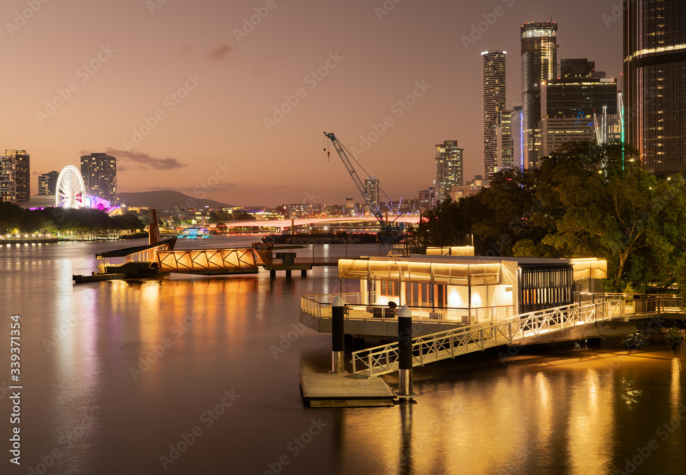 Brisbane city at sunset with a beautiful glow showing the new boardwalk city cat taxi terminal and Brisbane wheel