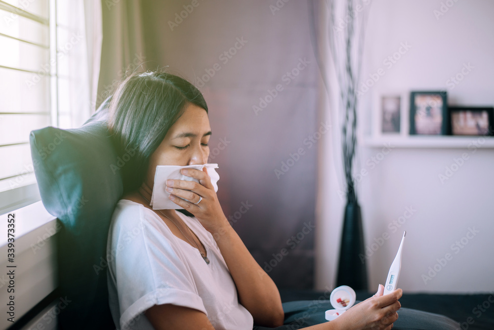 Sick asian woman holding a digital thermometer or measures the temperature Sick asian woman holding a digital thermometer or measures the temperature