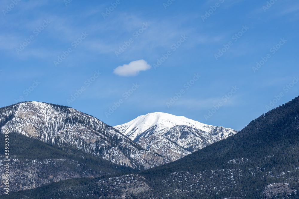 view of the mountain range with trees and snow on it sunny spring day.