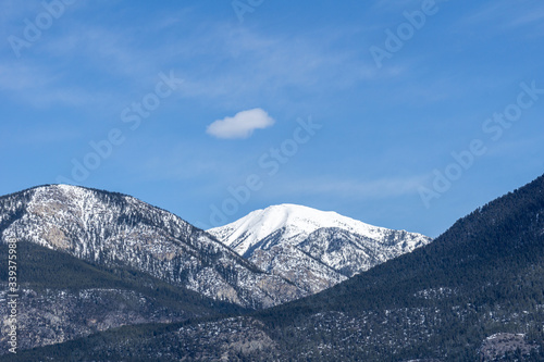 view of the mountain range with trees and snow on it sunny spring day. © olegmayorov