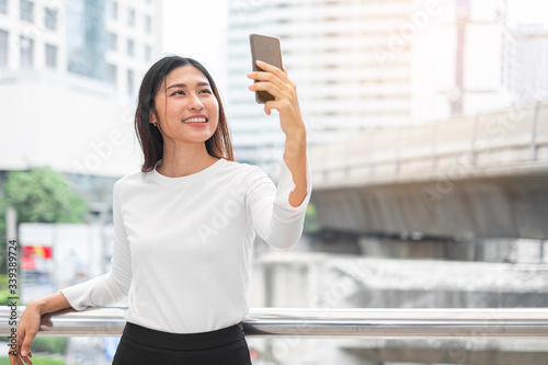 Portrait of young Asian beautiful woman taking selfie with smartphone in street city of Bangkok Thailand