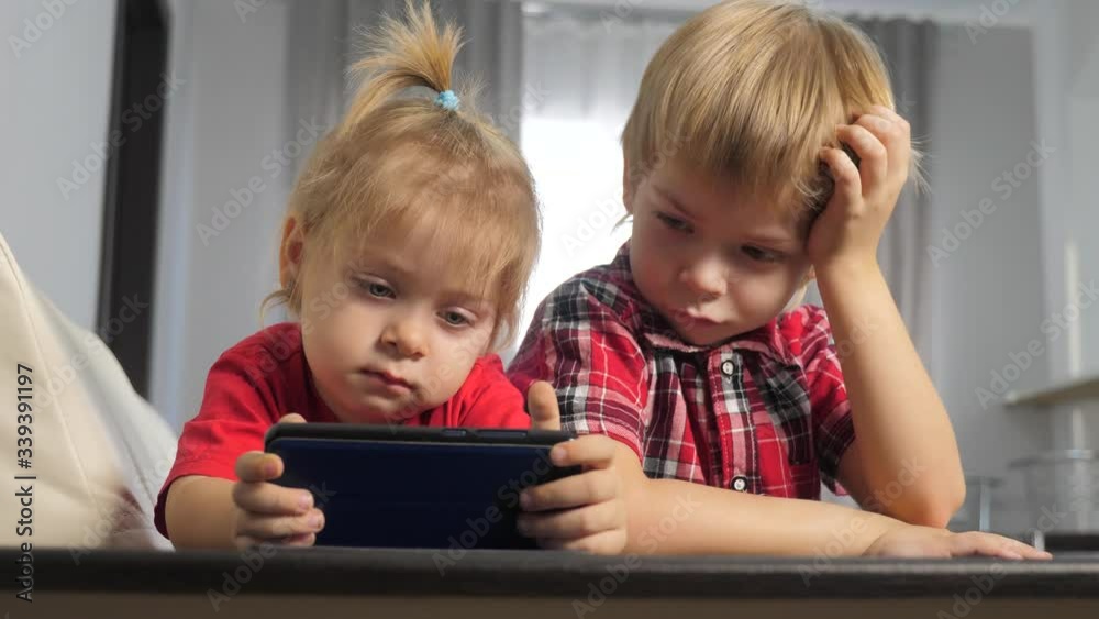 children watch online video lifestyle cartoons on a smartphone. kids little boy and girl brother sister watch online streaming broadcasting the phone children watch online video lifestyle cartoons on a smartphone. kids little boy and girl brother sister watch online streaming broadcasting the phone