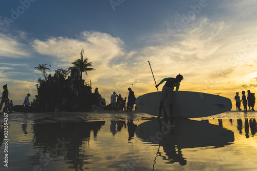 sunset over the beach with surfer standing with people around © yihchang