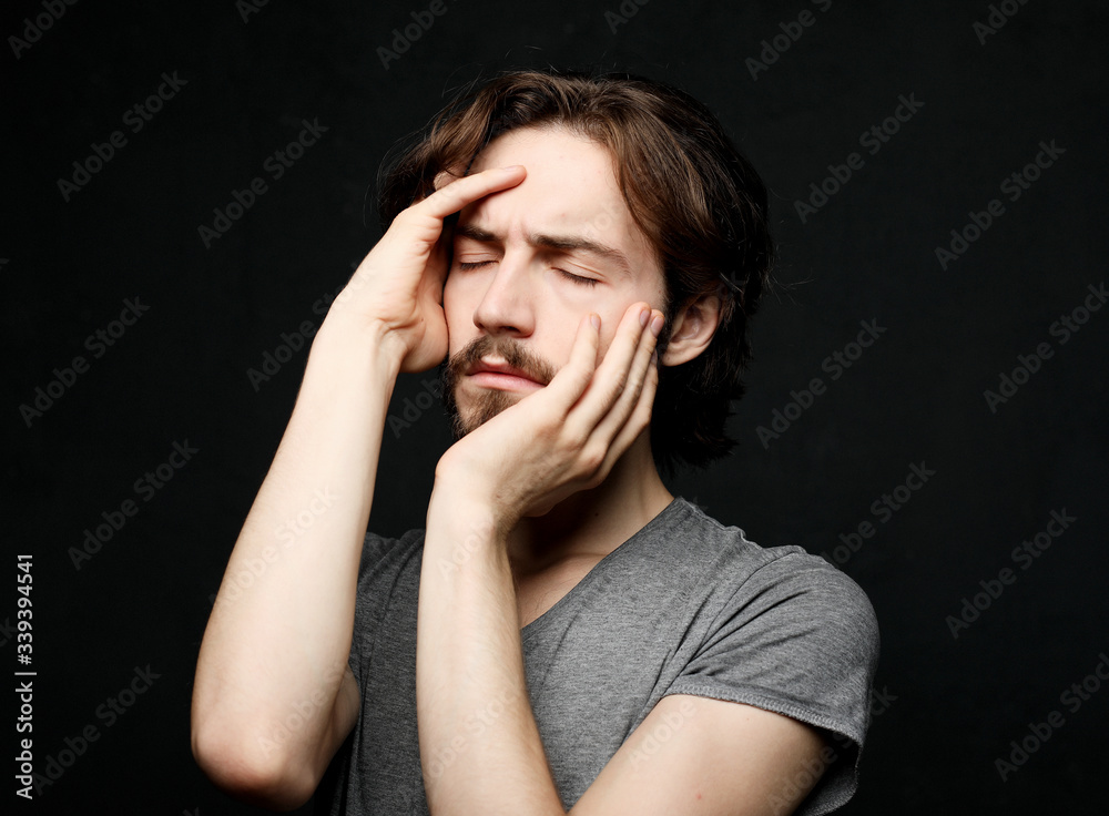 unhappy man touching his forehead over black background unhappy man touching his forehead over black background