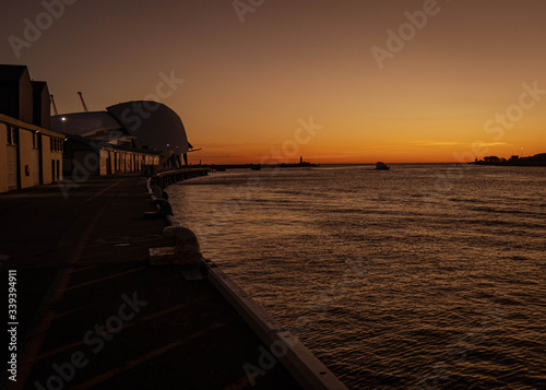 Southern hemisphere sunset at the Ferry pier, Fremantle Port, Perth, Western Australia. Impressive bright warm colors behind nice architectural building and smooth sea.
