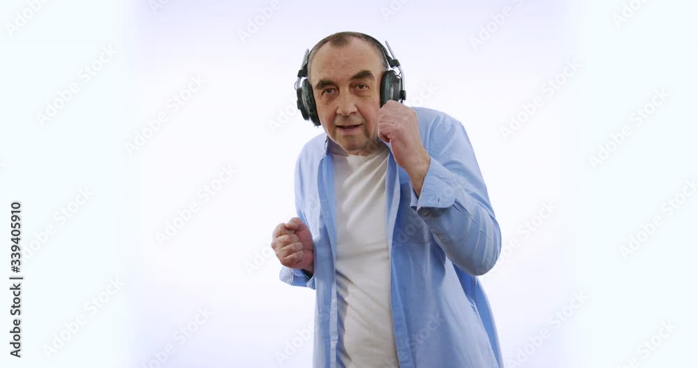 Slow motion of happy enderly man in wireless headphones dancing enjoying music. Modern devices, lifestyle and health concept. Slow motion of happy enderly man in wireless headphones dancing enjoying music. Modern devices, lifestyle and health concept.