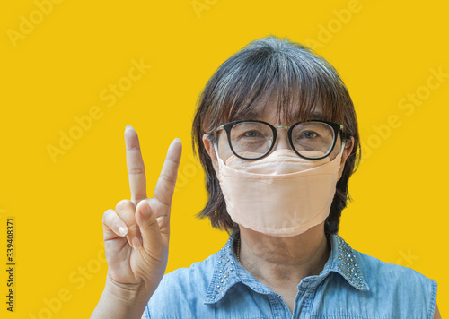 Female wearing face hygienic surgical mask for protection outbreak spreading coronavirus Covid- 19 standing showing two fingers victory sign or peace sign  victory winner infection outbreak coronaviru