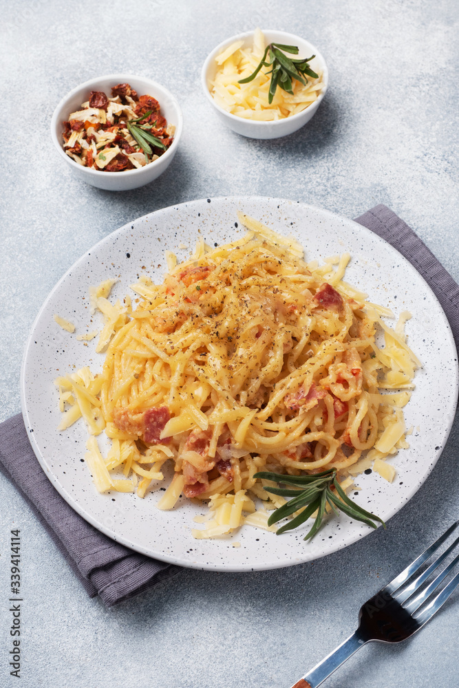 Pasta spaghetti with bacon egg cheese on a plate with spices. Traditional Italian dish Carbonara. Grey concrete table Pasta spaghetti with bacon egg cheese on a plate with spices. Traditional Italian dish Carbonara. Grey concrete table