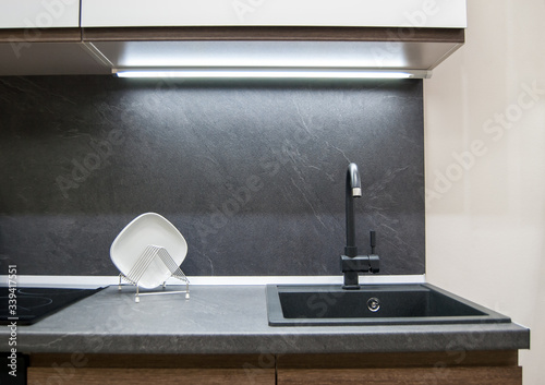 dark gray laminate worktop with black faux stone sink with faucet in a modern kitchen