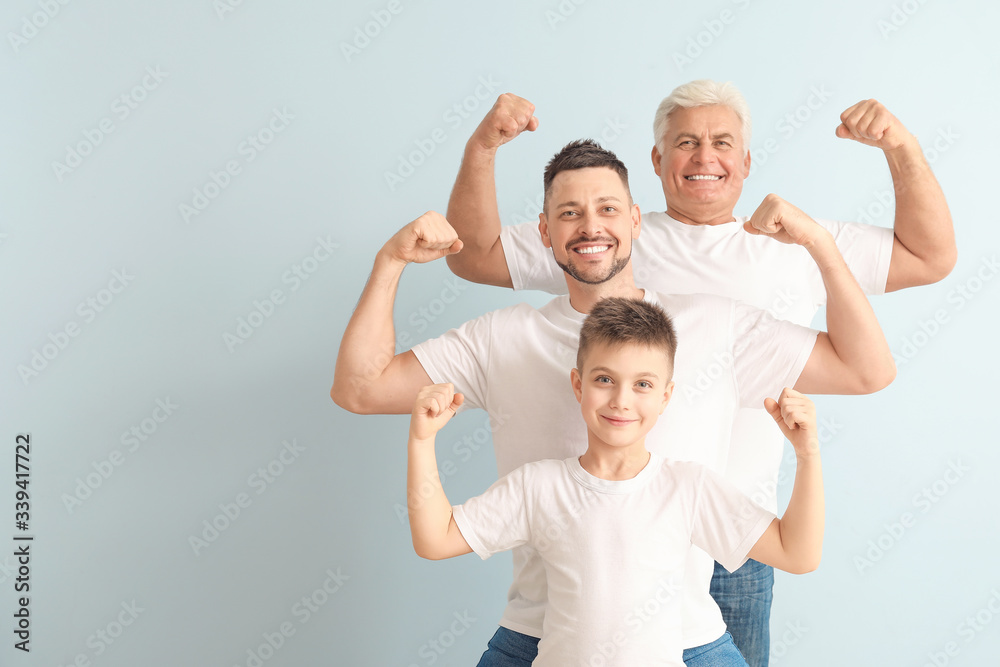 Man with his father and son showing muscles on color background - obrazy, fototapety, plakaty 