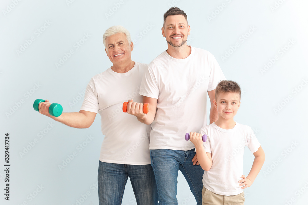 Man with his father and son holding dumbbells on color background Man with his father and son holding dumbbells on color background