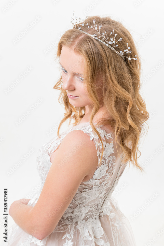 Romantic young bride isolated on white in white lace wedding dress with makeup and wavy blonde hair with pearl jewelry getting ready in bride's morning. Fine art wedding. Romantic young bride isolated on white in white lace wedding dress with makeup and wavy blonde hair with pearl jewelry getting ready in bride's morning. Fine art wedding.