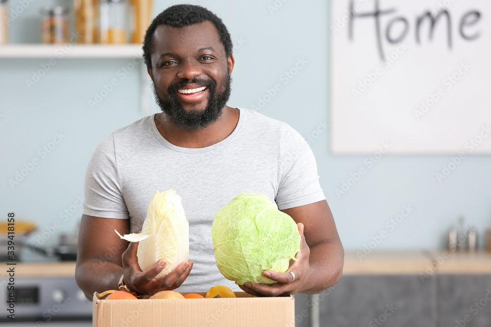 Fototapeta premium African-American man unpacking fresh products from market in kitchen