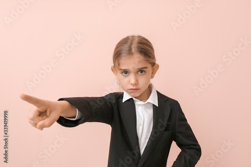 Tableau sur toile Little businesswoman showing something on color background