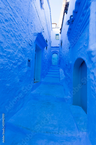 Old blue door in an alley in Chefchaouen, the blue city of Morocco. Urban concept © marcos