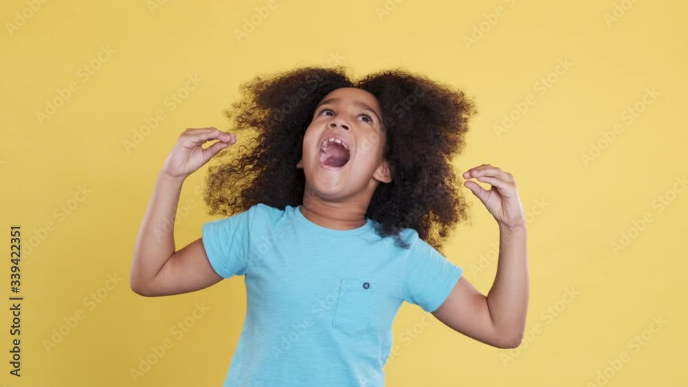 Little Dark-skinned Cutie Shows Comic or Comedian Gestures with her Hands. Clever, Talented Girl Have Fun. Concept of Imagination, Creativity, Childhood Development. Ridiculous, Amusing Emotions. Little Dark-skinned Cutie Shows Comic or Comedian Gestures with her Hands. Clever, Talented Girl Have Fun. Concept of Imagination, Creativity, Childhood Development. Ridiculous, Amusing Emotions.