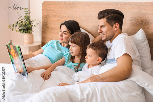 Happy family reading book in bedroom at home