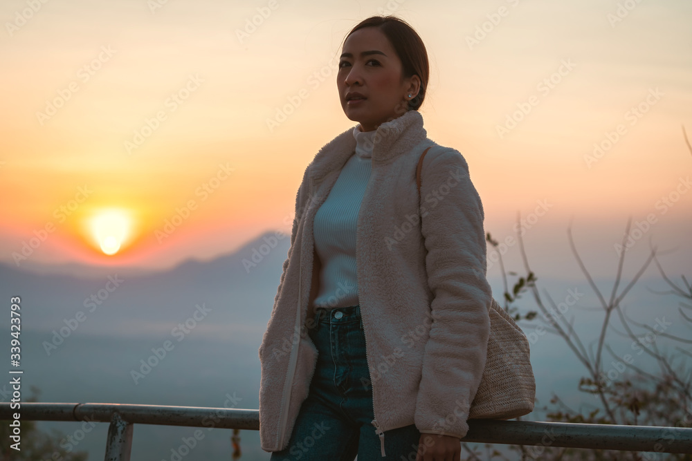 tourist women in white Winter coat and jeanes in relaxing Emotional The winter with blur background mountain sunrise in the morning at Phutok hill view point, Chiangkhan, Loei Province, Thailand. tourist women in white Winter coat and jeanes in relaxing Emotional The winter with blur background mountain sunrise in the morning at Phutok hill view point, Chiangkhan, Loei Province, Thailand.