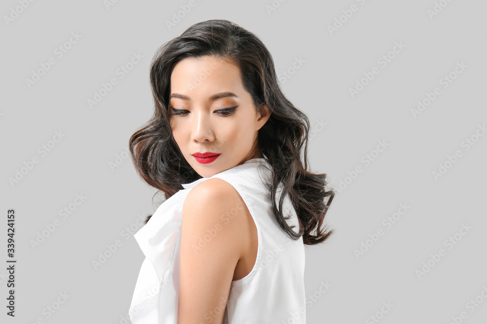 Young Asian woman with beautiful hair on grey background Young Asian woman with beautiful hair on grey background